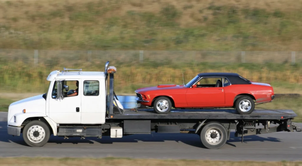 classic red car loaded on the back of a flatbed tow truck